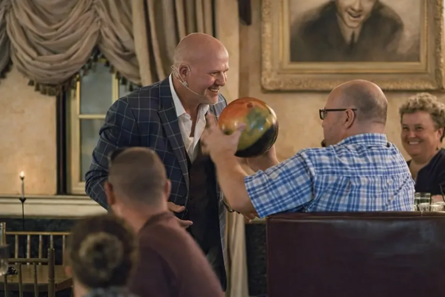 Mike DiDomenico laughing with audience member holding bowling ball during interactive performance at Club Arcada