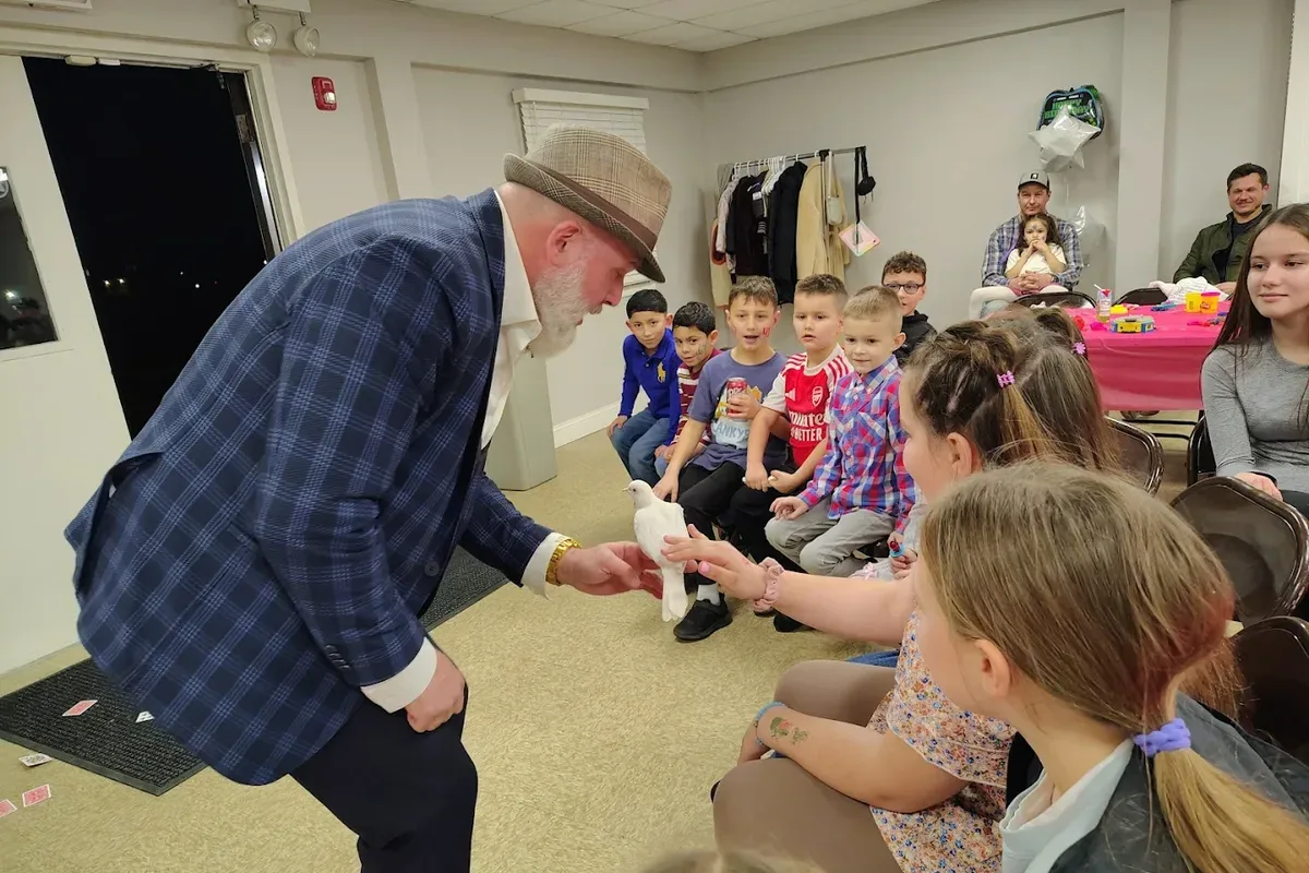 Mike DiDomenico letting children pet white dove at birthday party meet and greet