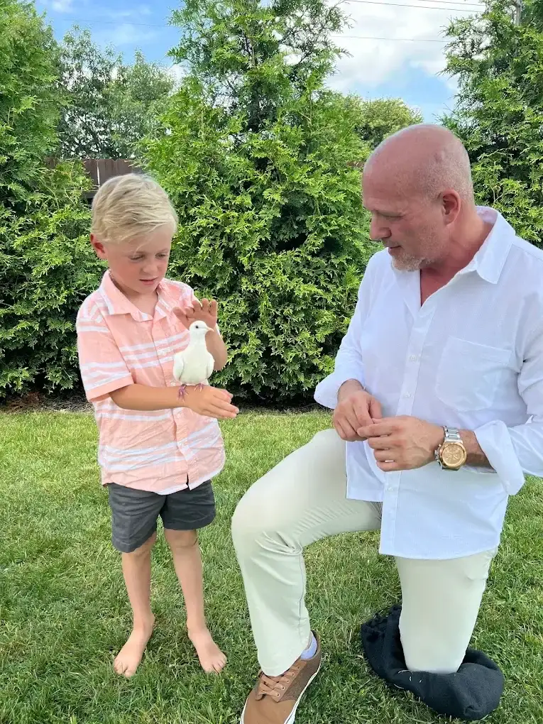 Boy gently holding white dove outdoors during birthday party meet and greet