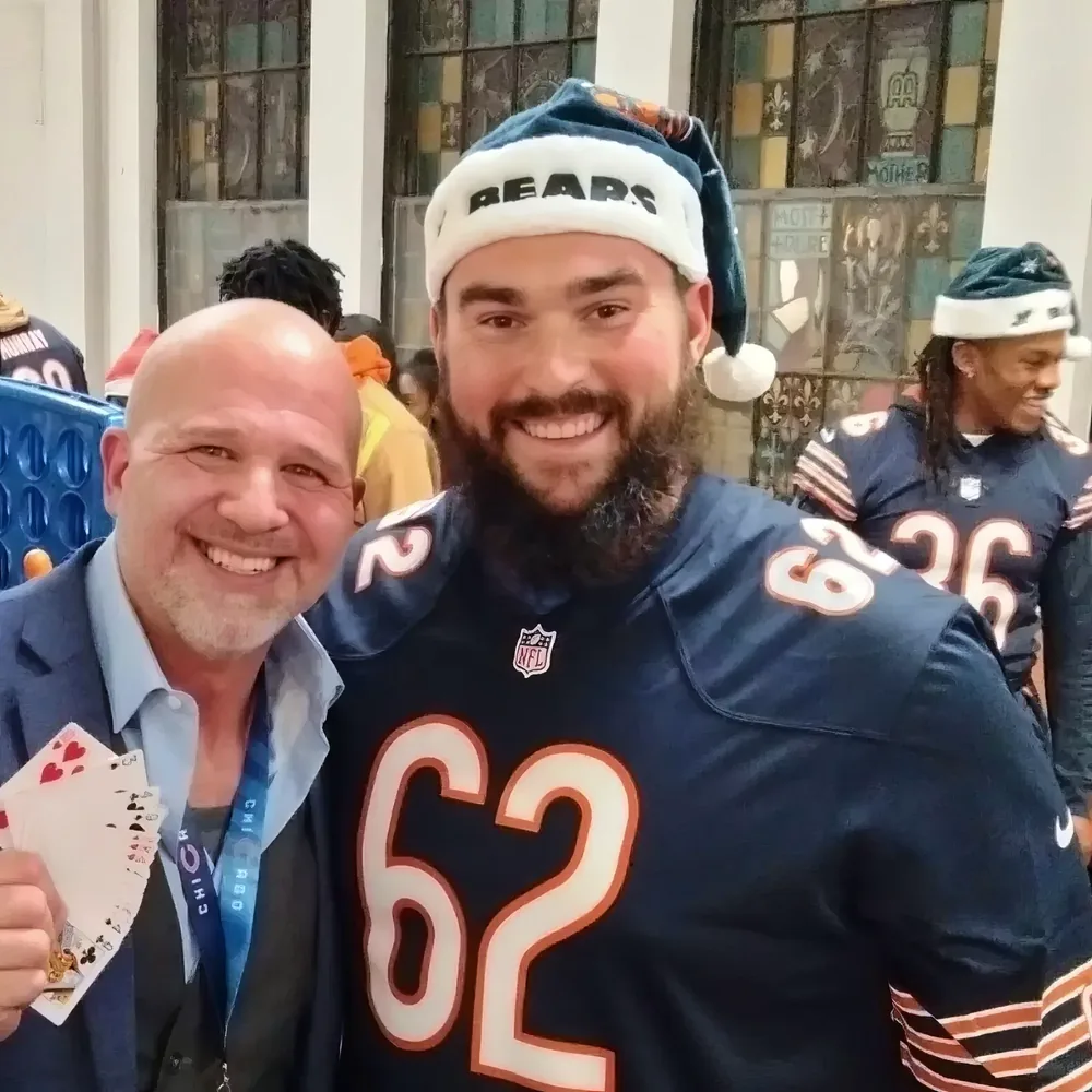 Mike DiDomenico performing close-up magic for Chicago Bears players at holiday event