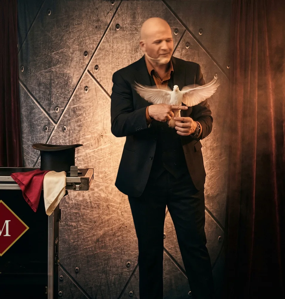 Mike DiDomenico in black suit holding white dove with wings fully spread on stage at Club Arcada