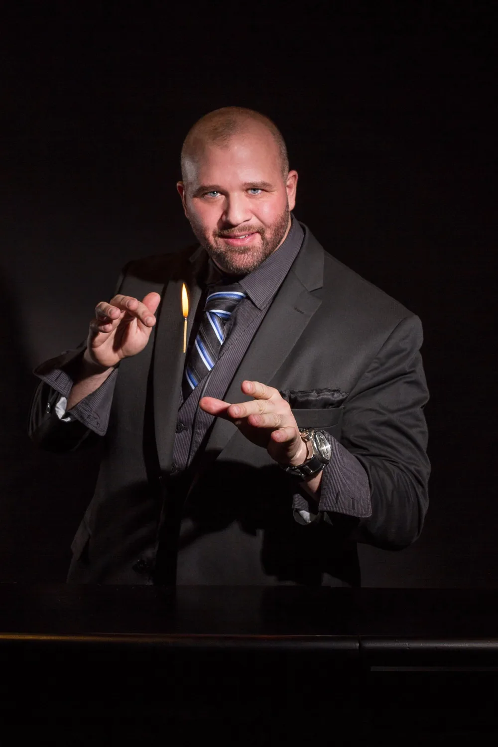 Mike DiDomenico in suit holding a flame between his fingers, professional studio portrait