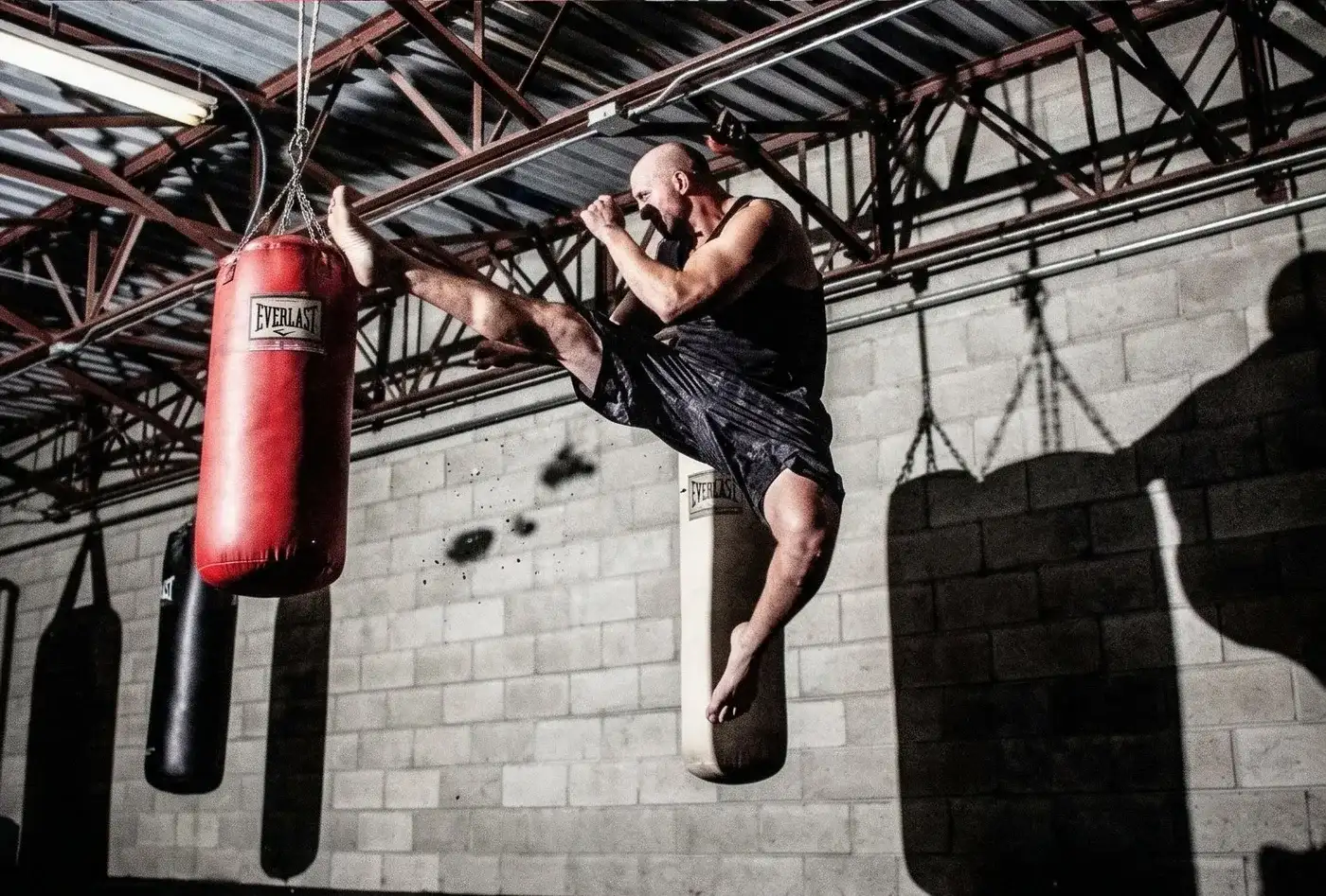 Mike DiDomenico executing a flying kick at an Everlast heavy bag showcasing his martial arts discipline