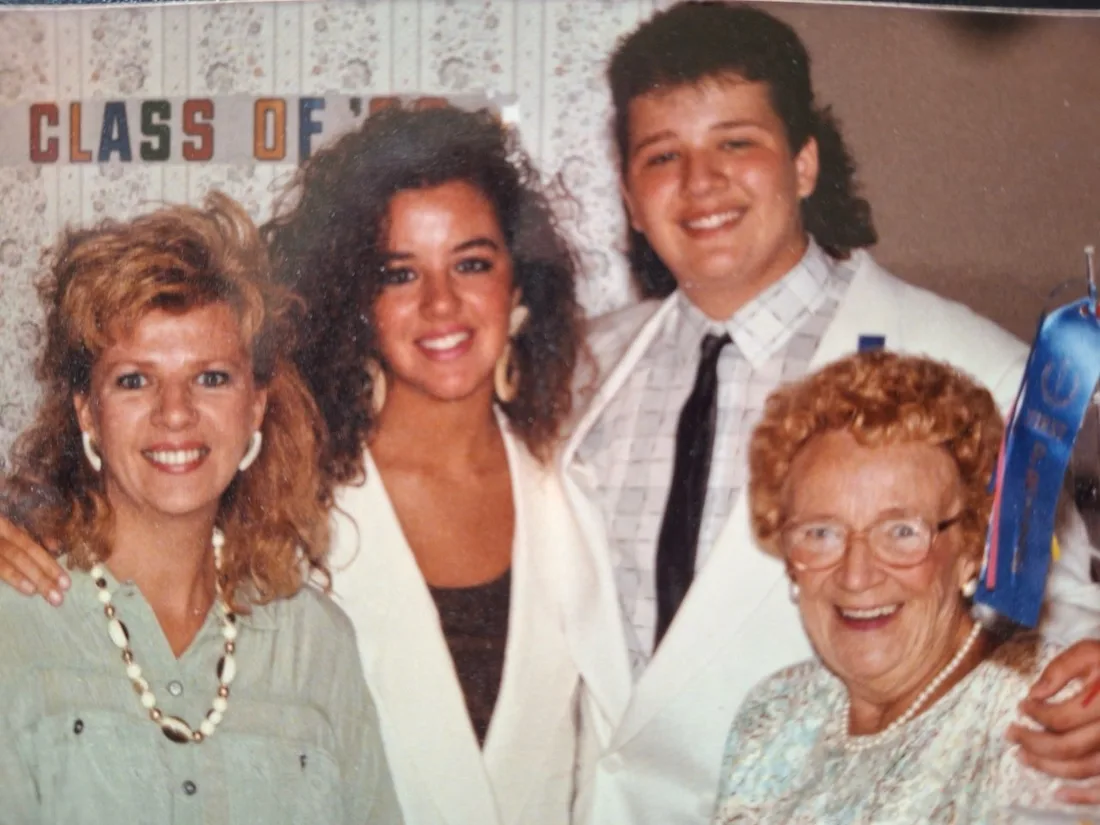 Young Mike DiDomenico at graduation with his grandmother holding a first-place blue ribbon for magic