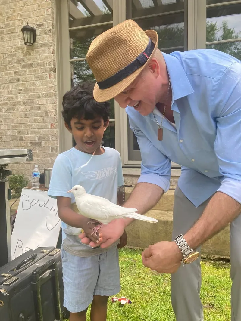 Young child holding white dove during meet and greet after magic show in backyard