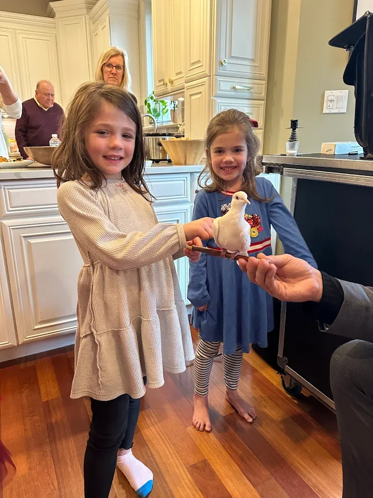 Two girls holding white dove at in-home private party in luxury kitchen
