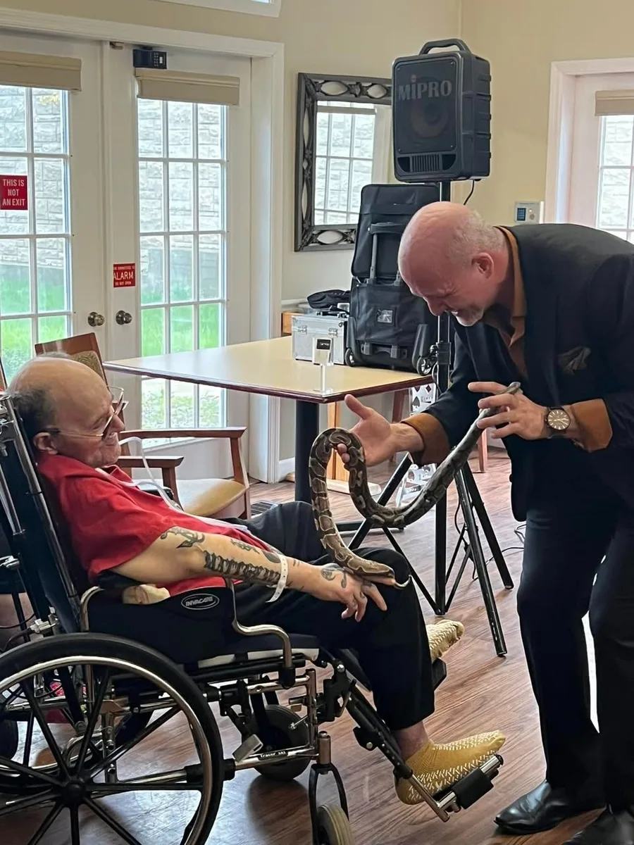 Mike DiDomenico gently showing python to elderly resident at senior living facility