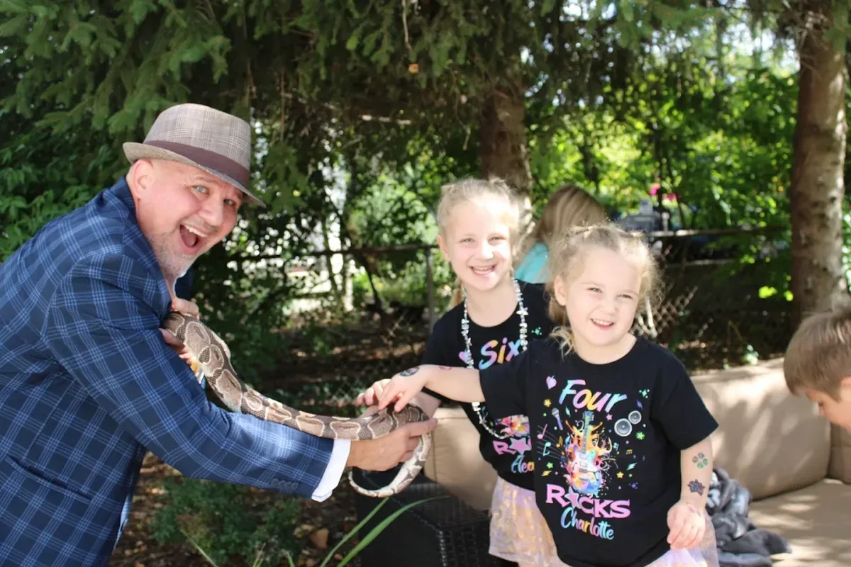 Mike DiDomenico with python and two laughing girls at backyard birthday party