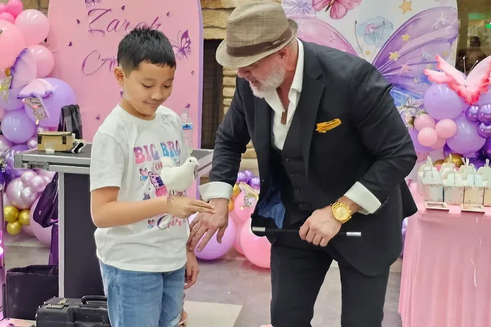 Boy holding white dove during meet and greet at butterfly themed birthday party